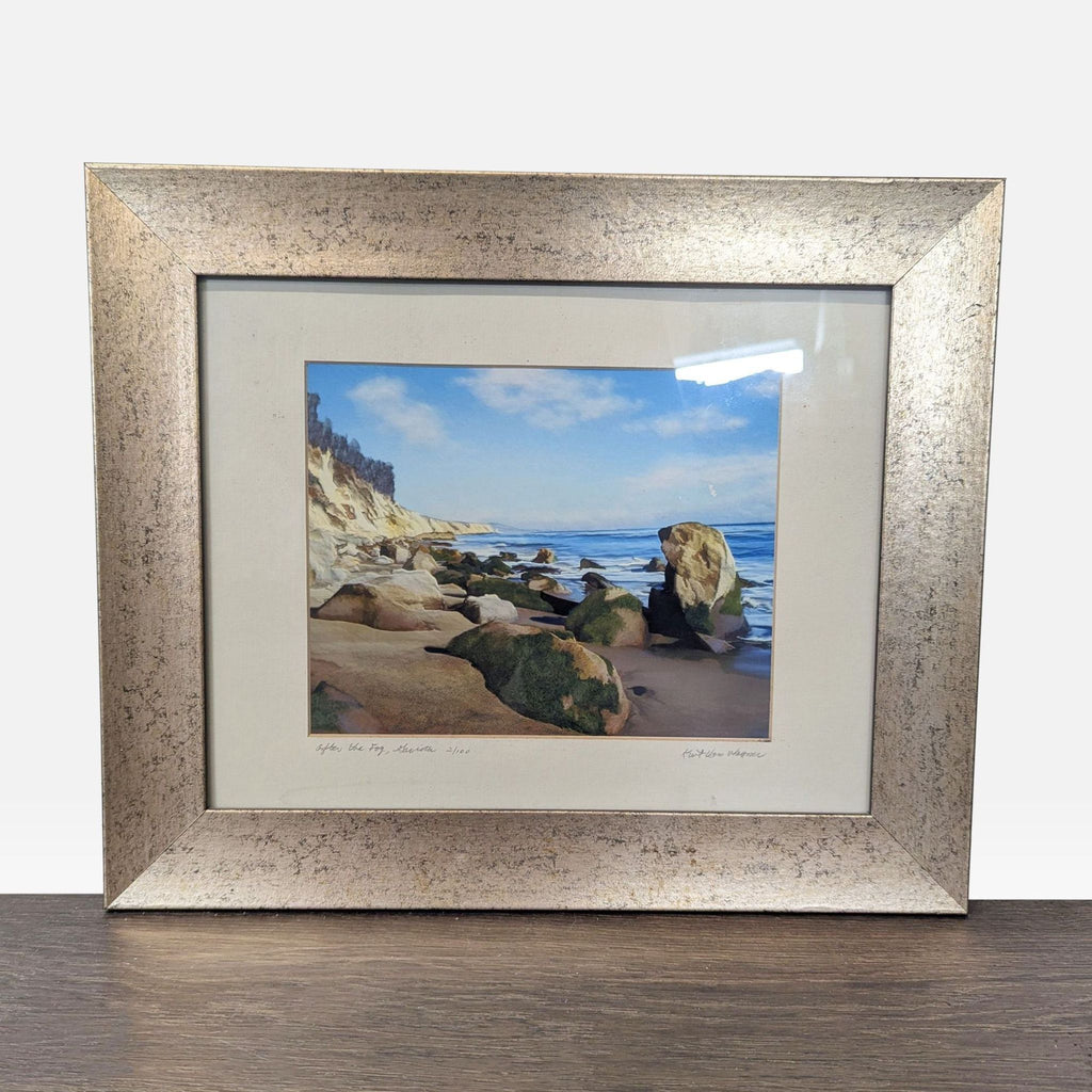 1. Framed coastal painting with rocky cliffs and calm sea, signed by artist, in a metallic frame, ready to hang.  