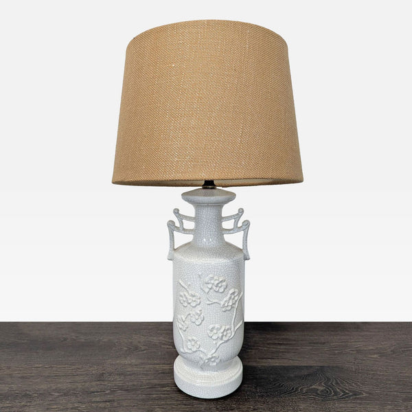 White ceramic table lamp with crackle glaze, floral design, and light brown textured shade.