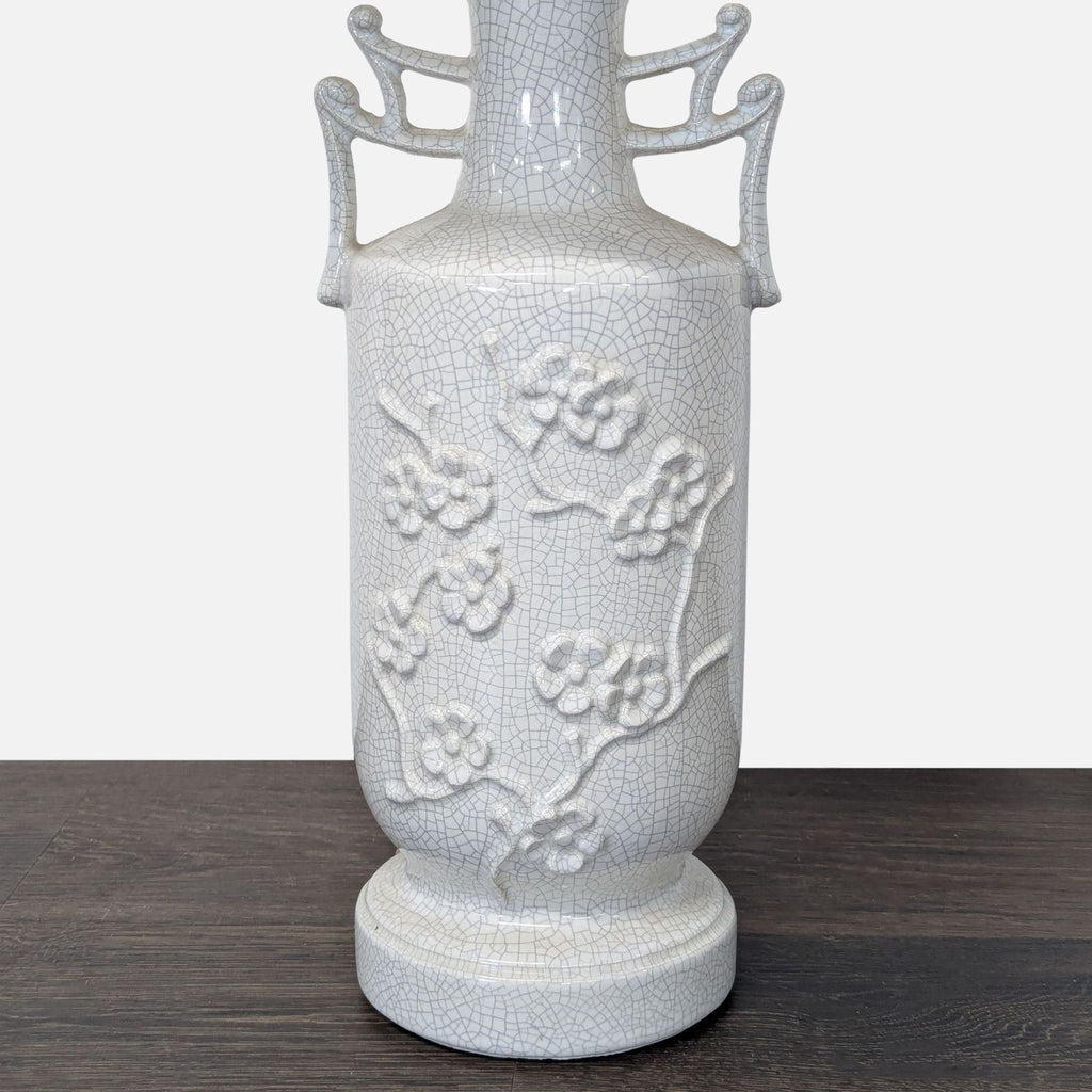 Table lamp featuring a white base with flower and branch motif and a tan fabric lampshade.
