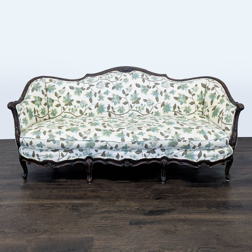Floral-patterned 3-seat sofa with carved wood frame and curved arms, upholstered in soft green and blue fabric.  