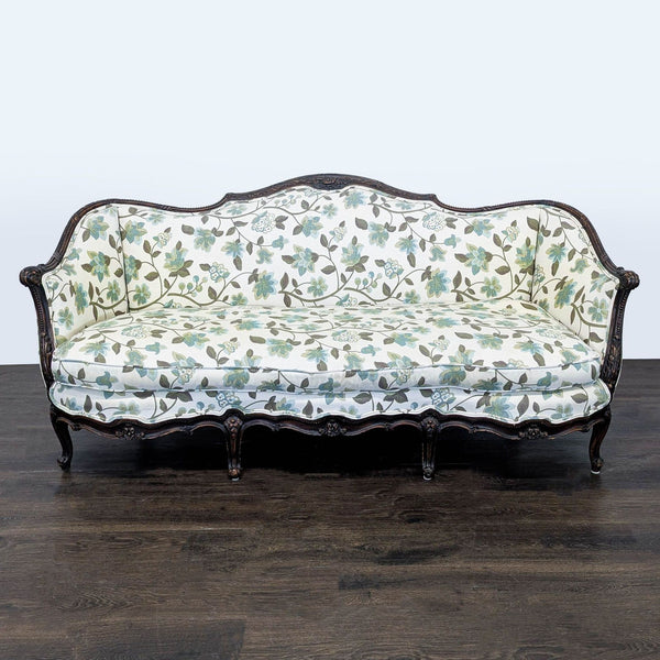 Floral-patterned 3-seat sofa with carved wood frame and curved arms, upholstered in soft green and blue fabric.  