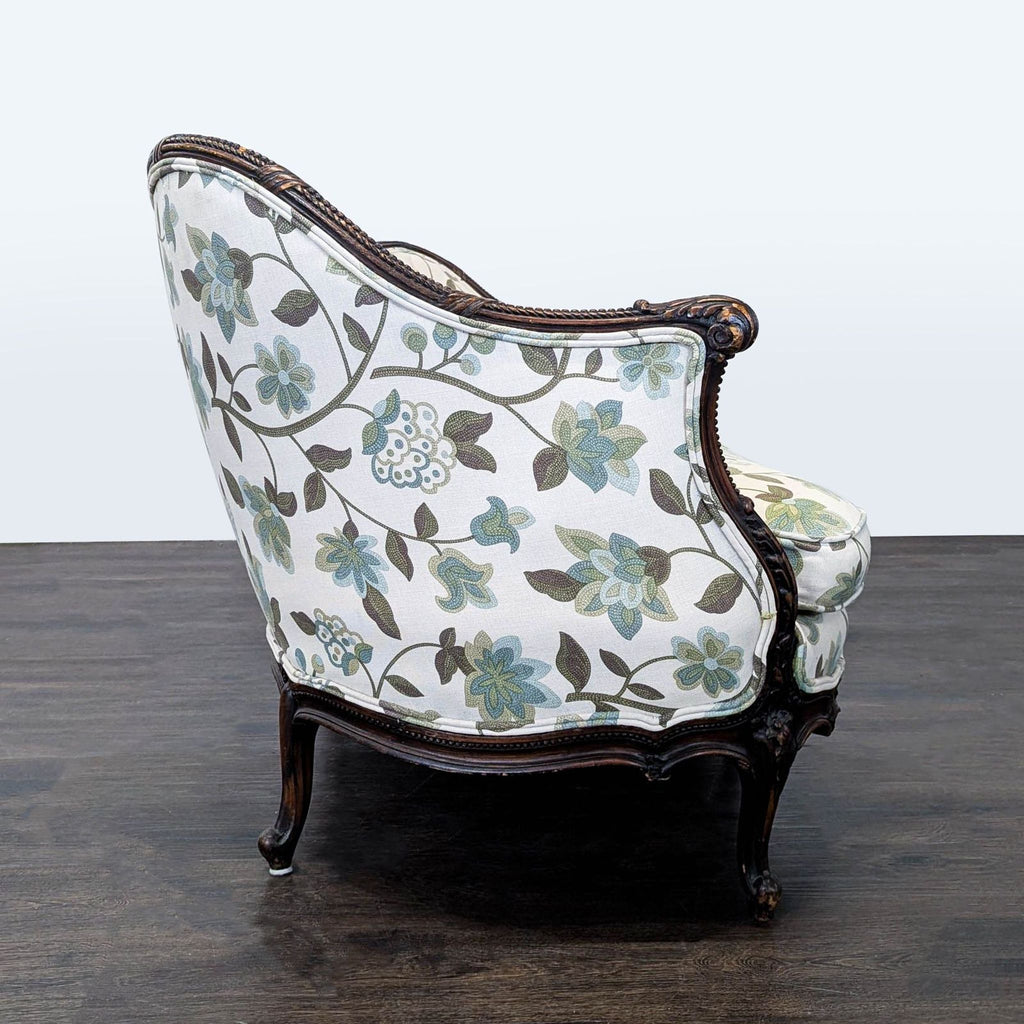 Side view of a vintage 3-seat sofa, showing floral upholstery in muted tones and detailed carved wood armrest.