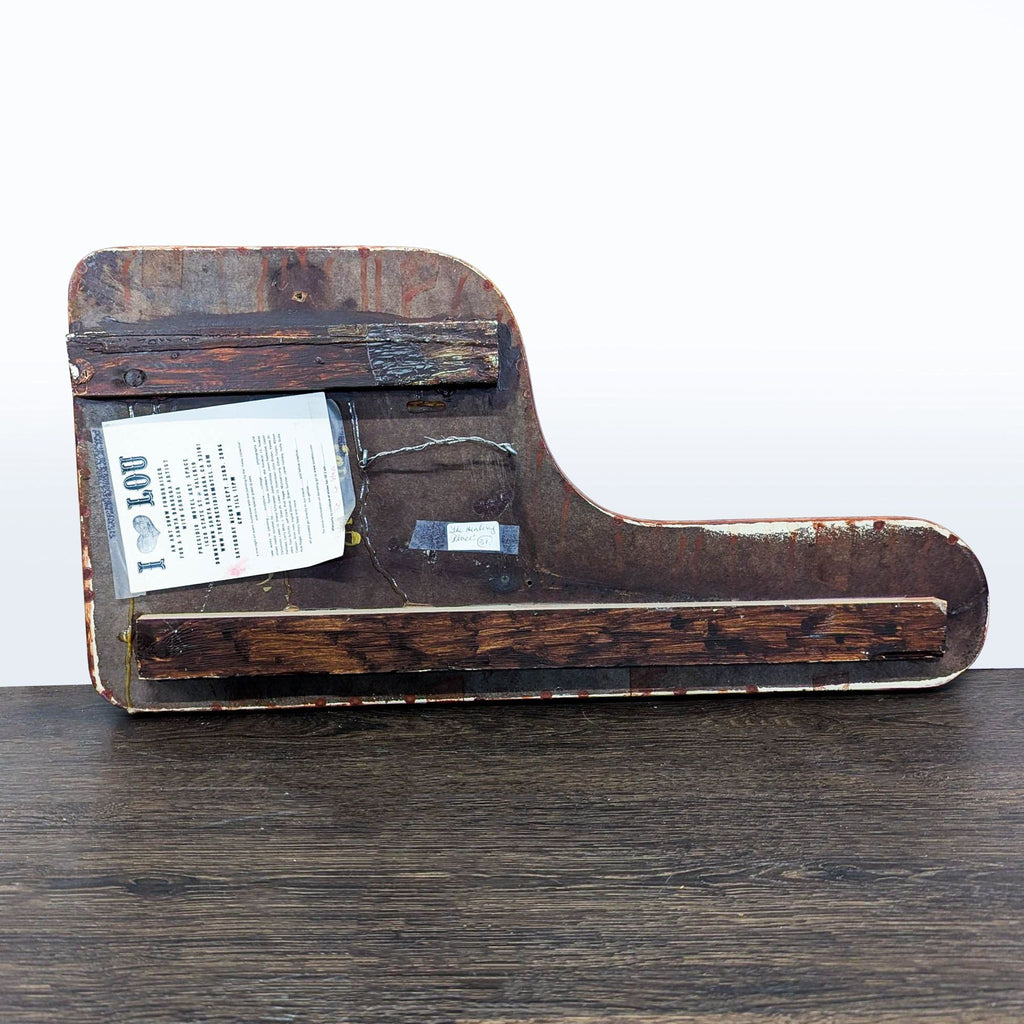 3. Back view of a shaped wooden art panel with hanging hardware and an attached information card.