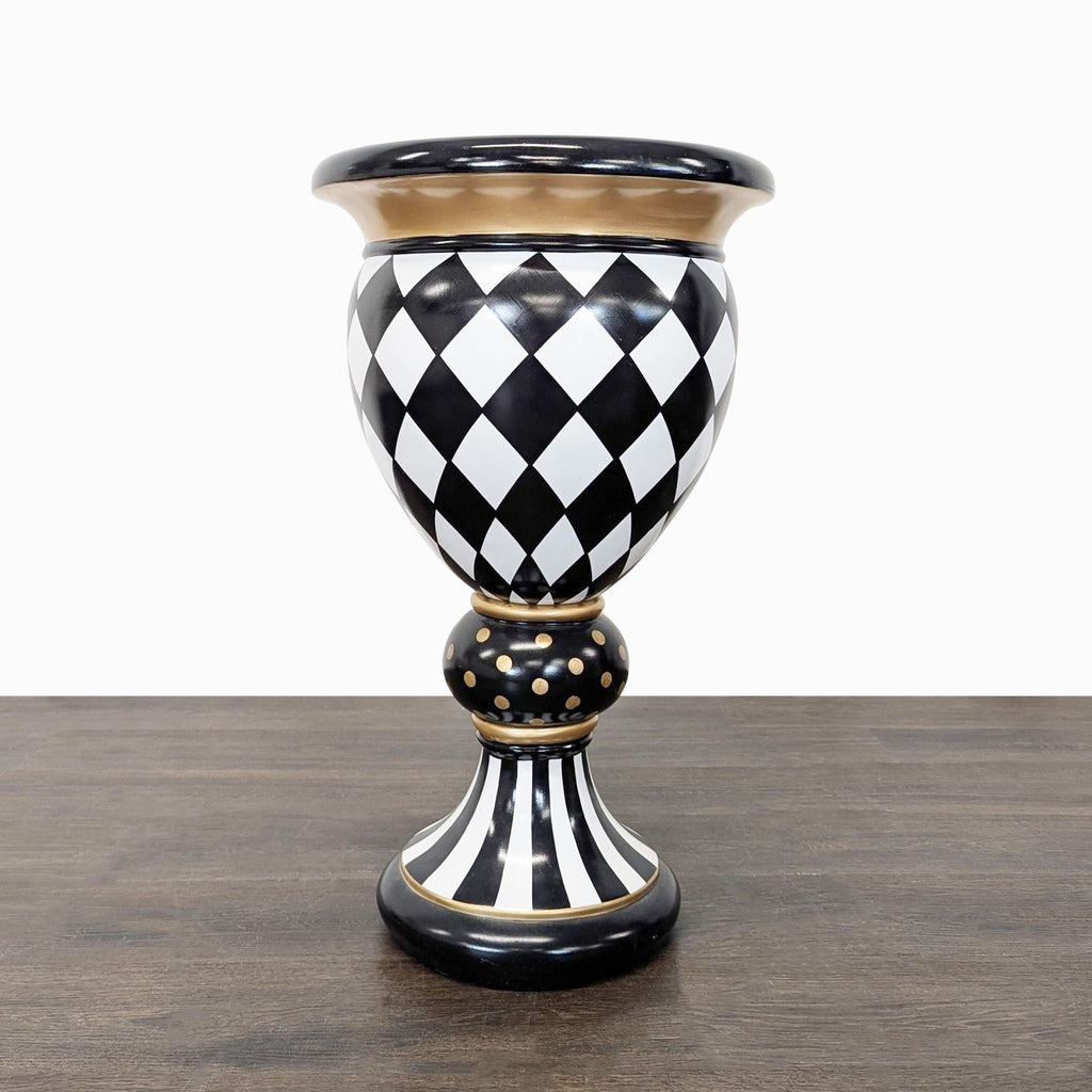MacKenzie-Childs vase with black and white harlequin pattern, gold accents, and a tall pedestal base.