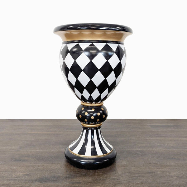 MacKenzie-Childs vase with black and white harlequin pattern, gold accents, and a tall pedestal base.