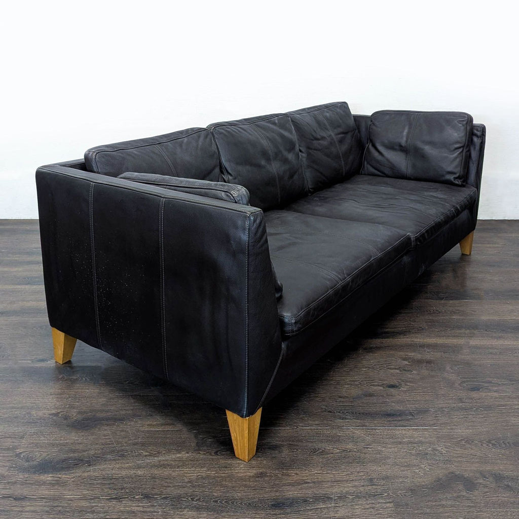 Modern Ikea three-seater sofa featuring leather upholstery and sturdy wooden legs for style and durability.