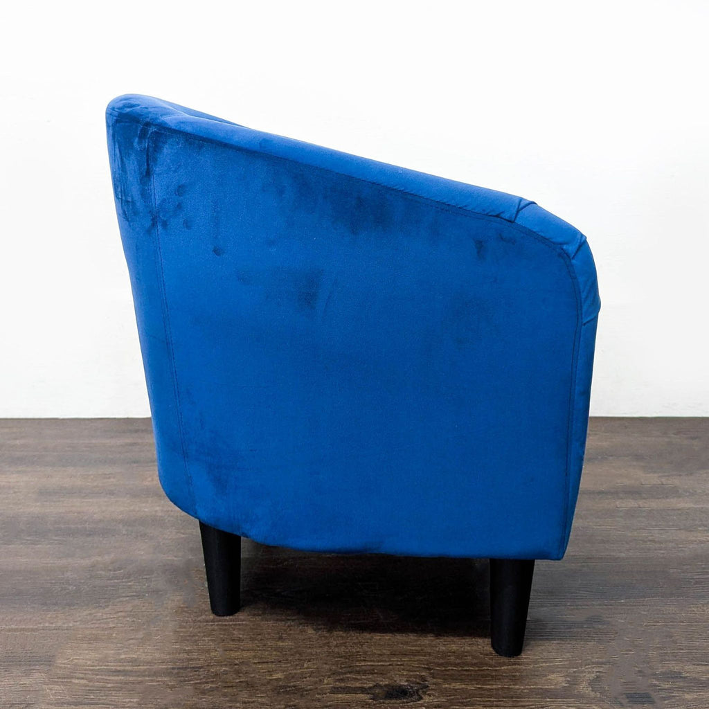 Contemporary blue velvet chair with supportive curved back and stable black legs; perfect for lounge spaces.