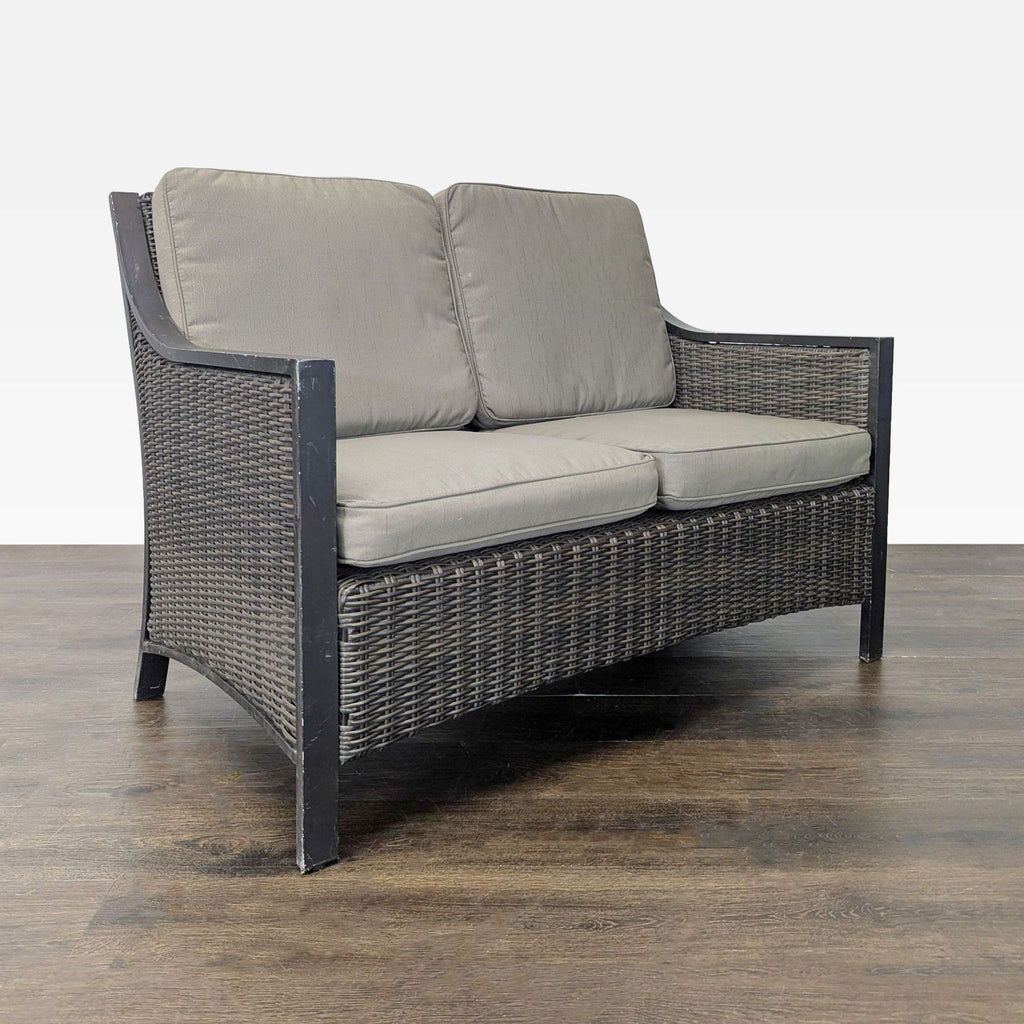 Weather-resistant loveseat featuring sturdy dark wicker and plush gray cushions, designed for outdoor comfort.