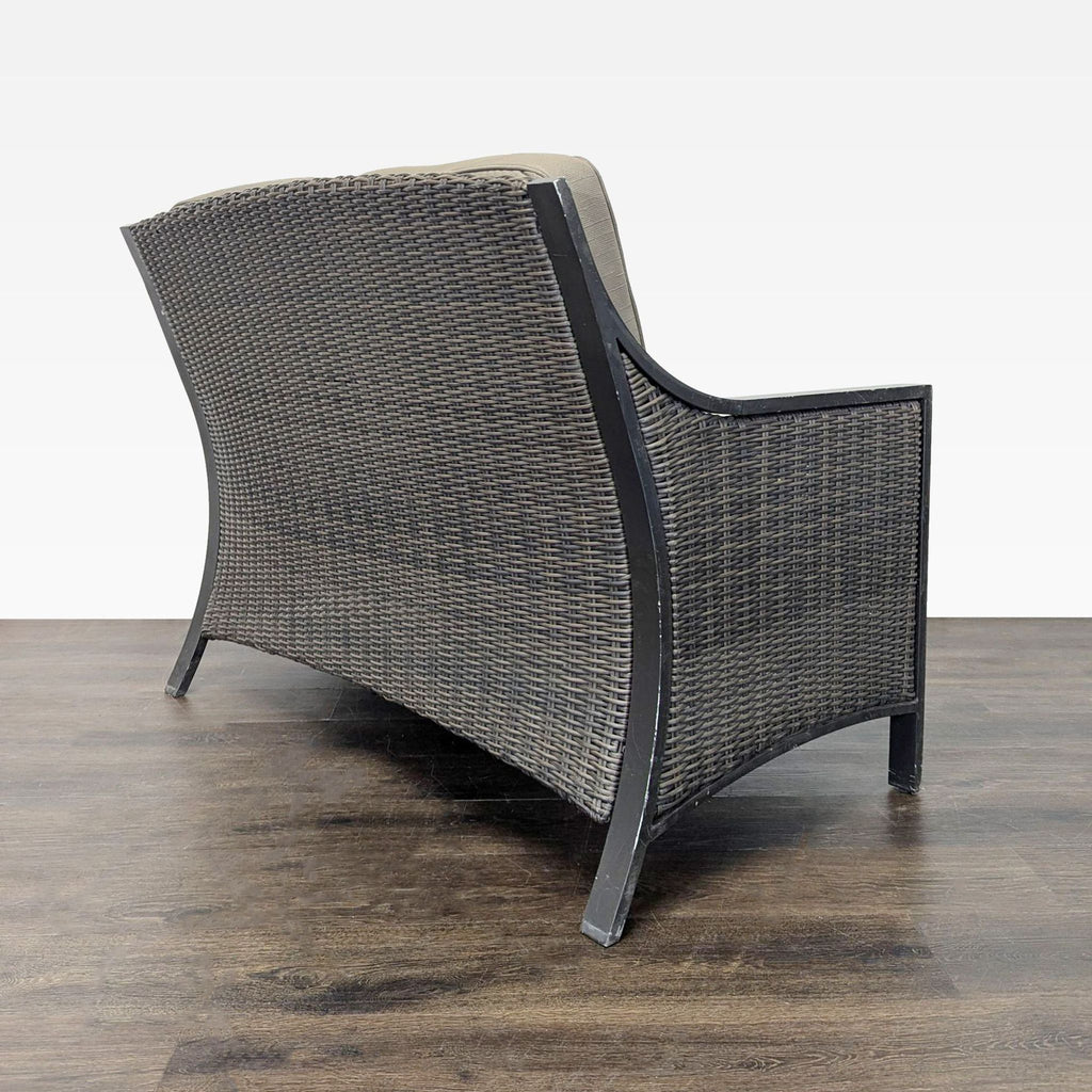 Cozy outdoor loveseat with all-weather wicker design and soft gray cushions, seats two people comfortably.
