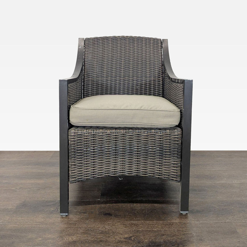 1. Woven rattan armchair with a beige cushion, viewed from the front, on a wooden floor against a white background.  