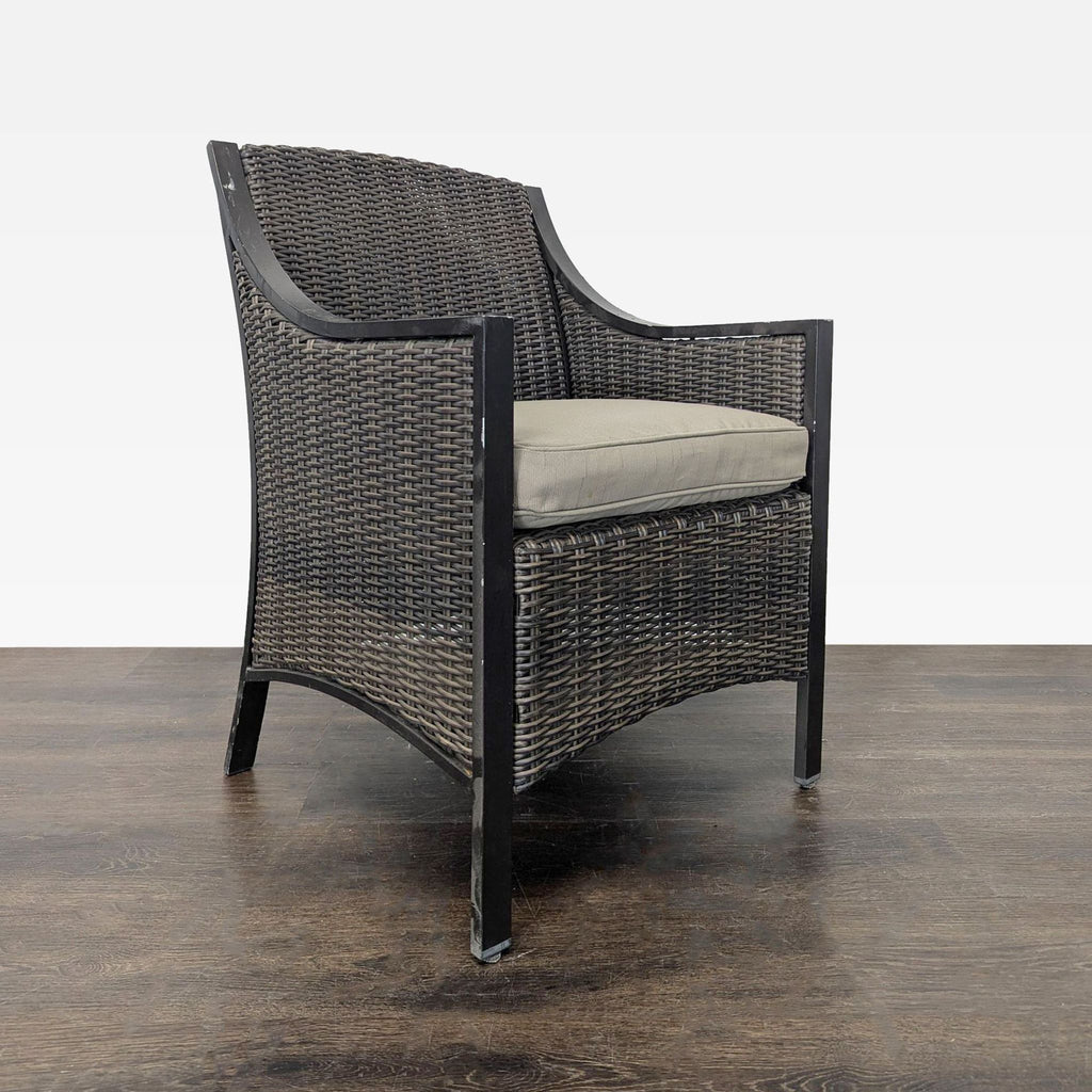 2. Angled view of a dark wicker chair with soft beige seat cushion and curved metal frame, indoor setting.  