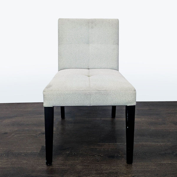 Crate & Barrel low back dining chair with button tufting and wooden legs, shown in a modern setting.  