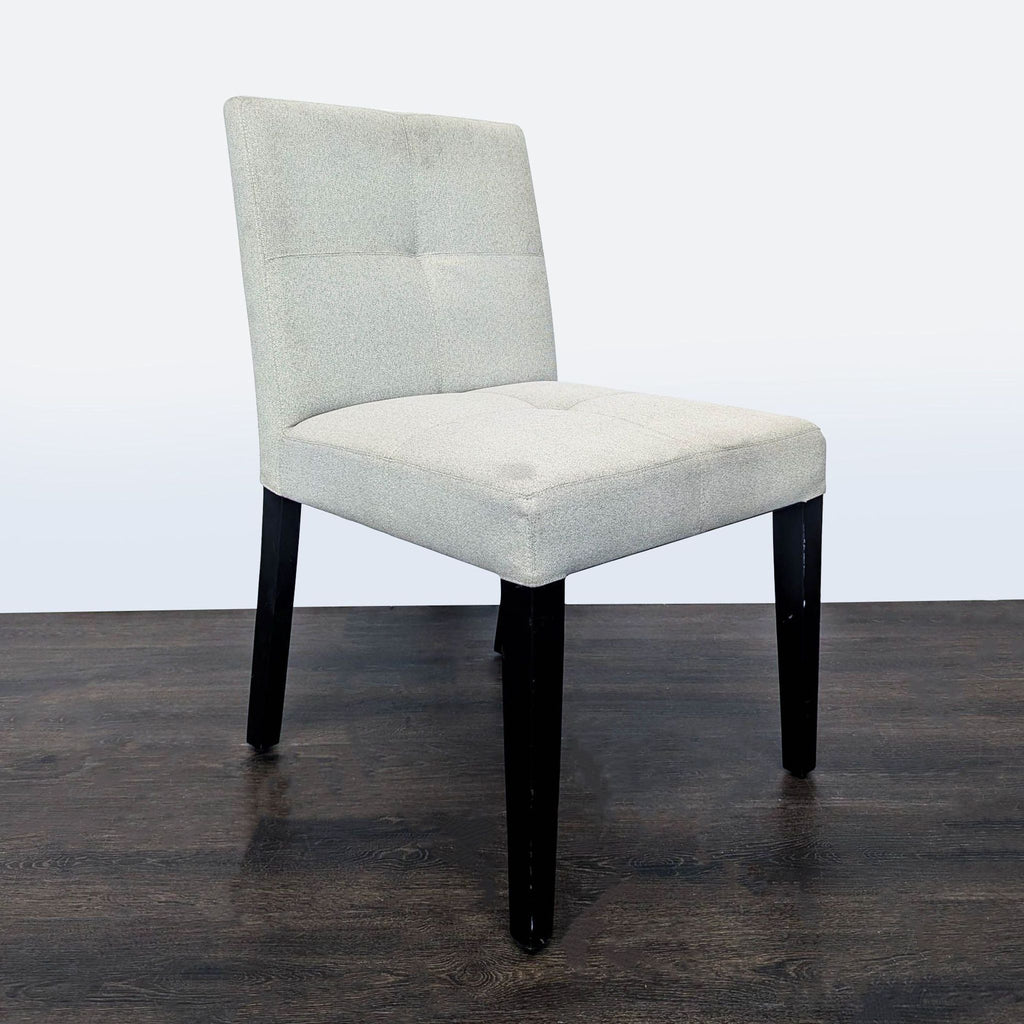 Button-tufted dining chair featuring wood legs, low back, from Crate & Barrel, ideal for dining rooms.  