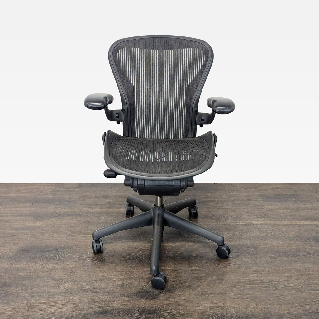 Herman Miller Aeron mesh office chair with adjustable armrests and ergonomic support, shown on a sturdy base.