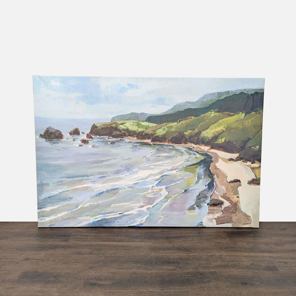 1. Framed coastal landscape print showing sandy shore and green hills, by Giantart.com, on a wooden floor.