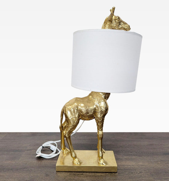 Gold giraffe-shaped table lamp with a white drum shade, ideal for quirky lighting decor.