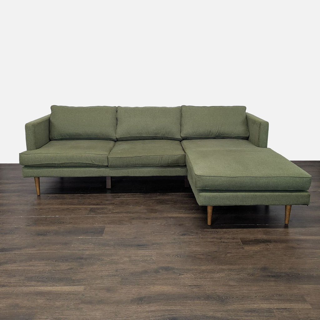 Modern green Joybird sectional with wooden legs and right-side chaise, offering spacious, plush seating.