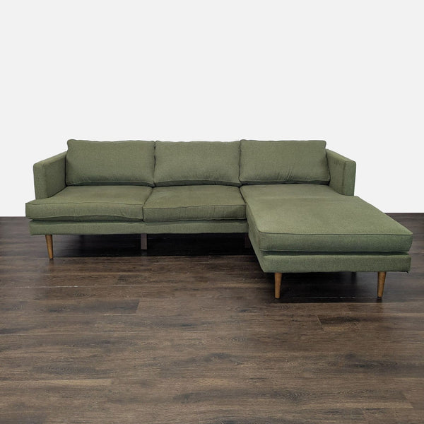 Modern green Joybird sectional with wooden legs and right-side chaise, offering spacious, plush seating.