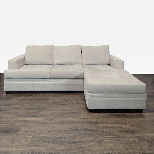 Living Spaces sectional sofa with beige fabric, chaise lounge, modern style, and comfortable plush cushions.  
