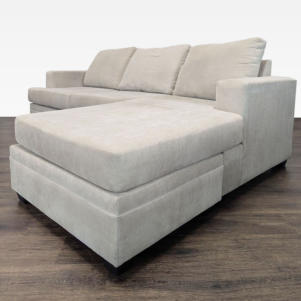 Beige Living Spaces sectional with spacious chaise, soft upholstery, sturdy armrests, and simple, modern design.  