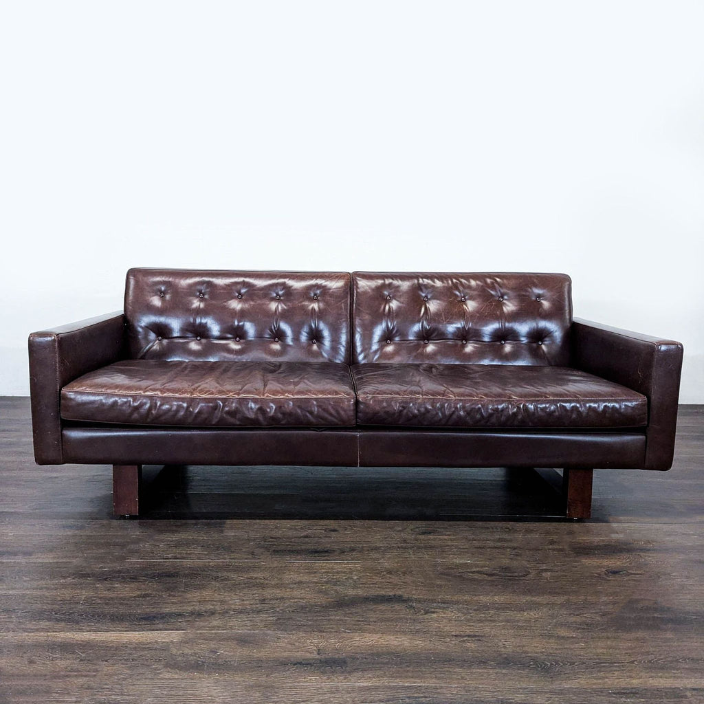 Room & Board Wells 3-seat sofa with brown tufted leather, wooden legs, and a modern, timeless design.