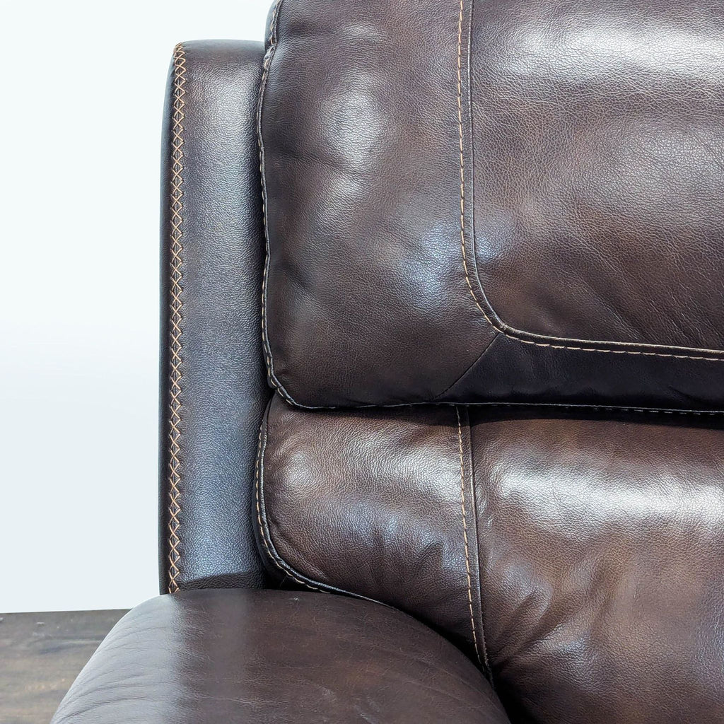 Comfortable two-seater loveseat in brown leather with wide arms and plush, supportive cushions.