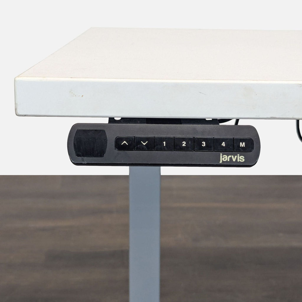 White Jarvis sit-stand desk featuring programmable buttons for customizable height adjustments in workspaces.  