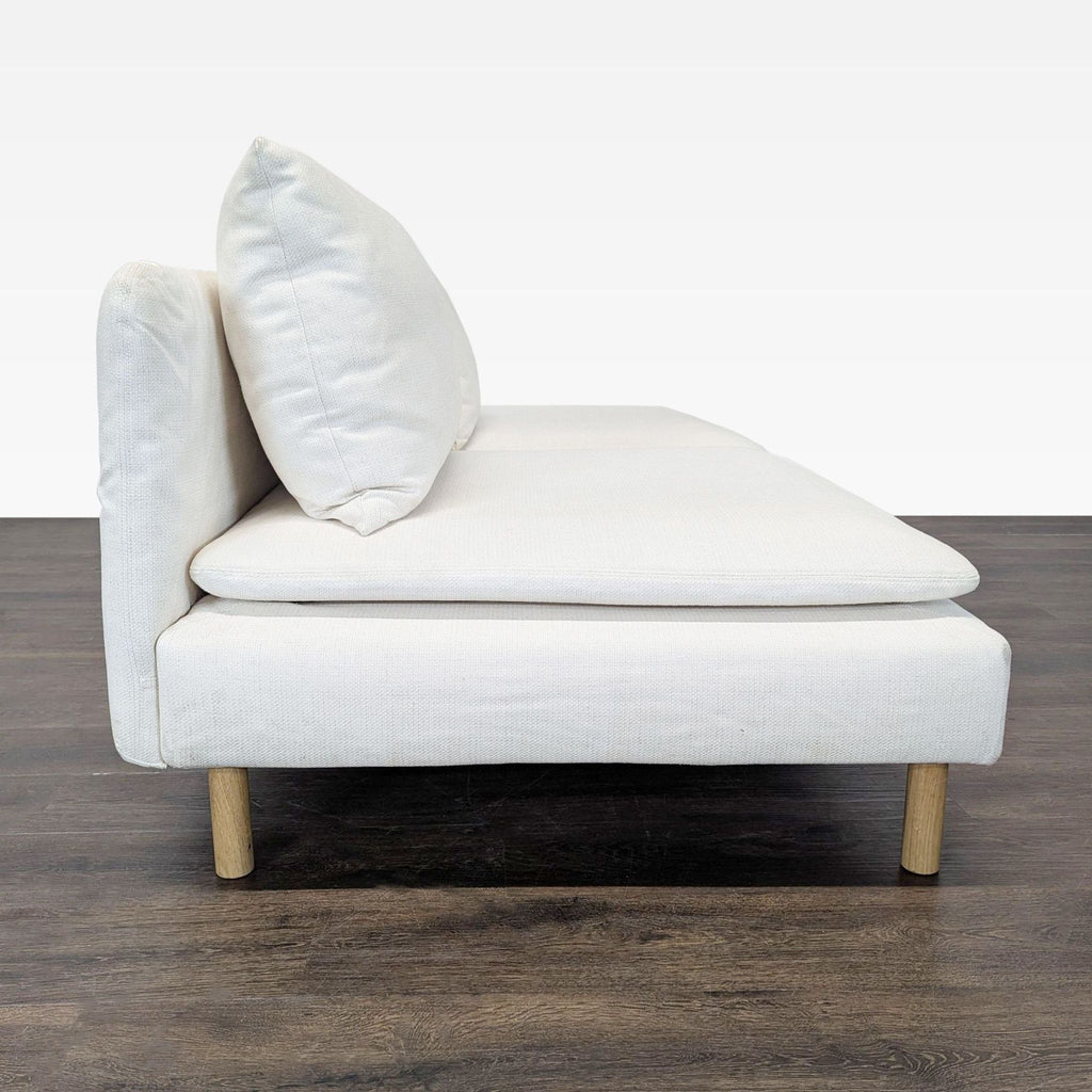 Compact Ikea loveseat, white upholstery with supportive cushions and wooden legs, stylish and practical seating.