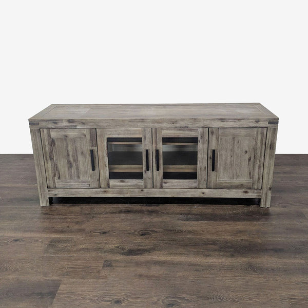 Rustic gray Macy’s media console with four doors, glass panels, and shelves for electronics and media storage.