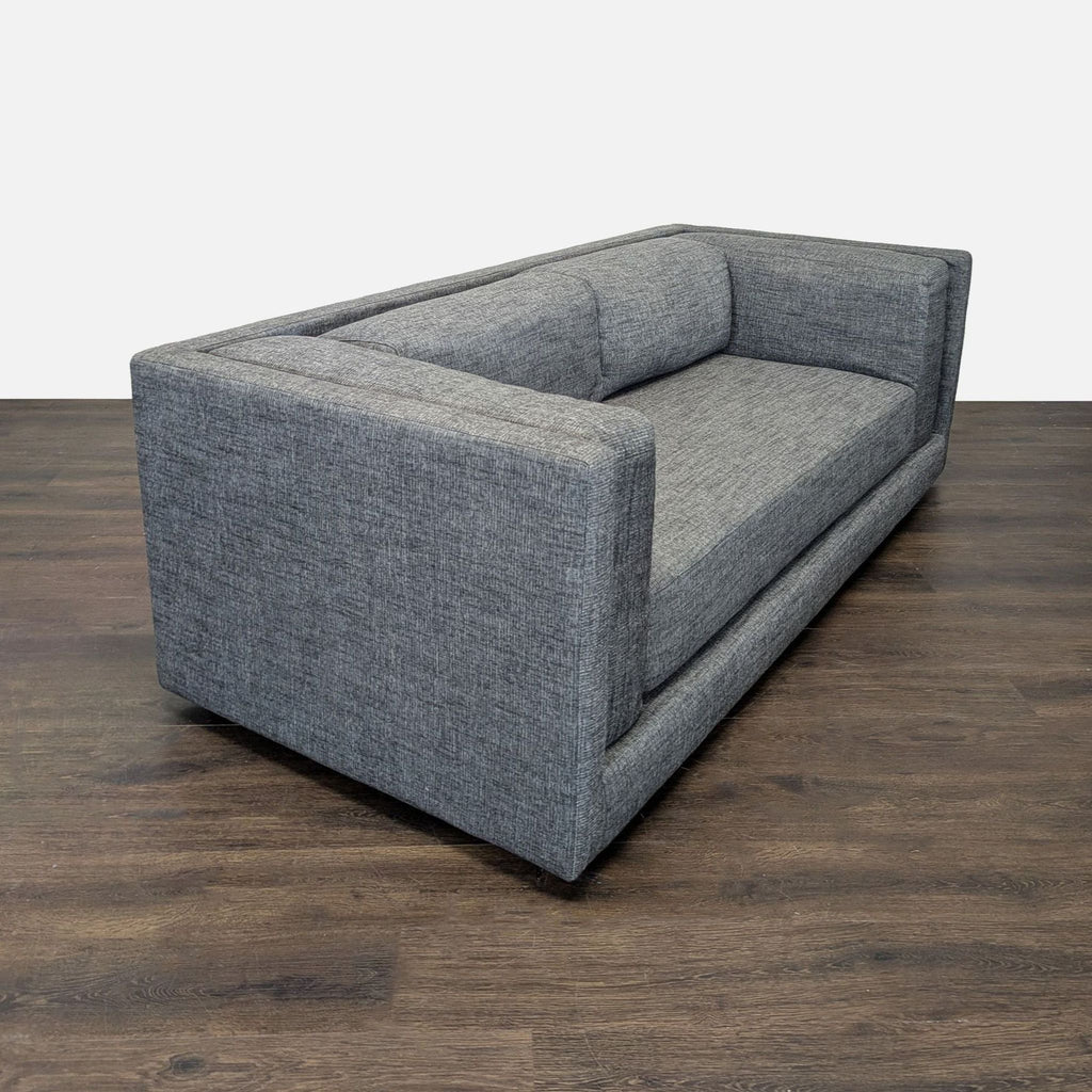 Modern CB2 sofa with three seats, neutral grey upholstery, and a sturdy, minimalist construction.