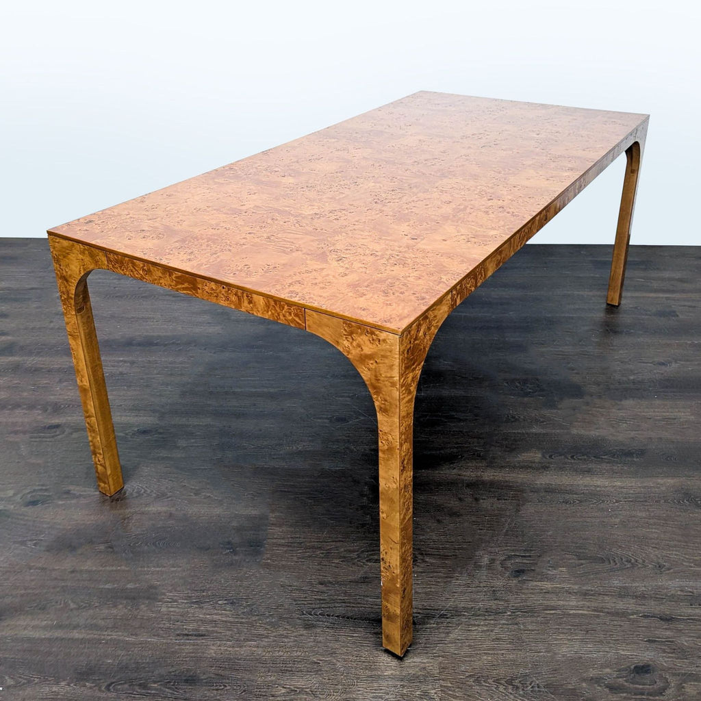 Modern CB2 table featuring fluid curves and burl wood veneer, echoing vintage style and architectural arches.