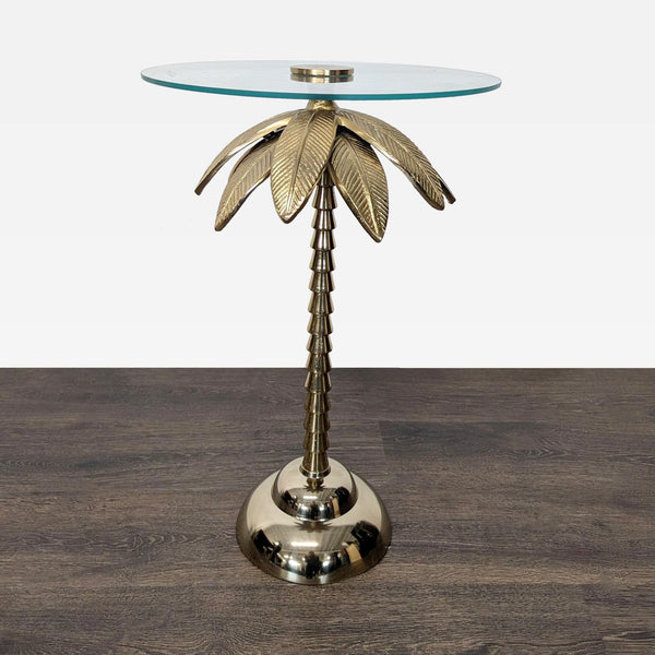 Glass side table with gold palm tree-shaped metal base and round glass top.  