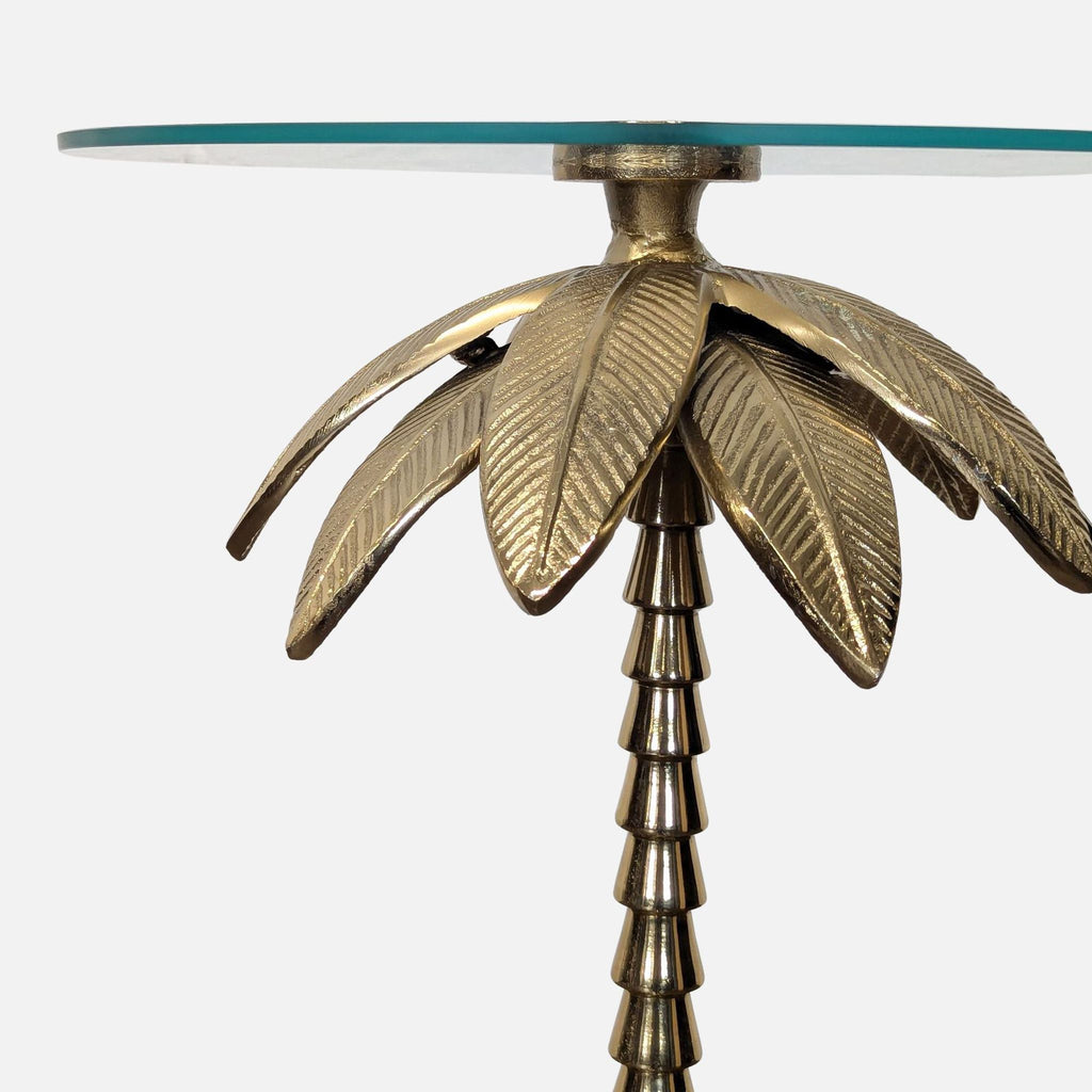 Side table featuring a clear glass top and metallic gold palm tree pedestal.