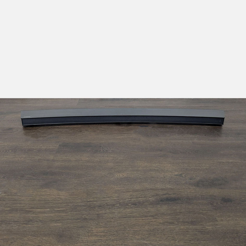 Back of Samsung curved TV displaying a clean finish, Samsung logo, and sturdy support stand.