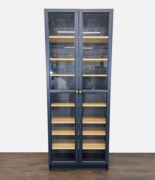 Ikea bookshelf with glass doors, light wooden shelves, and brass knobs for modern book display.