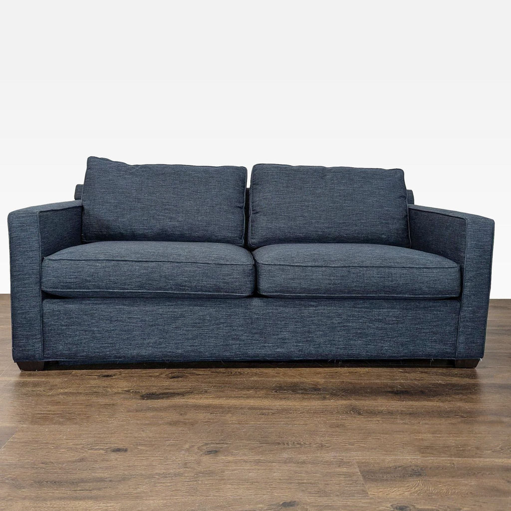 Crate & Barrel blue sleeper sofa with modern design, plush cushions, and sturdy armrests, shown in living room.