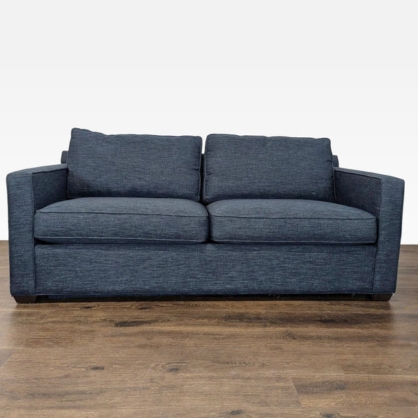 Crate & Barrel blue sleeper sofa with modern design, plush cushions, and sturdy armrests, shown in living room.