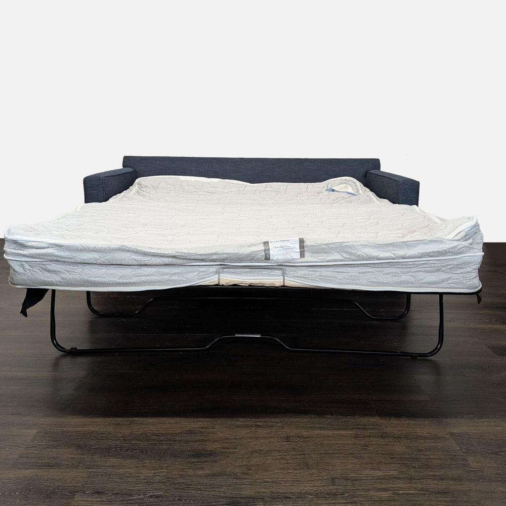 Deep blue Crate & Barrel sleeper sofa with comfortable seating and back cushions, ideal for relaxing or sleeping.