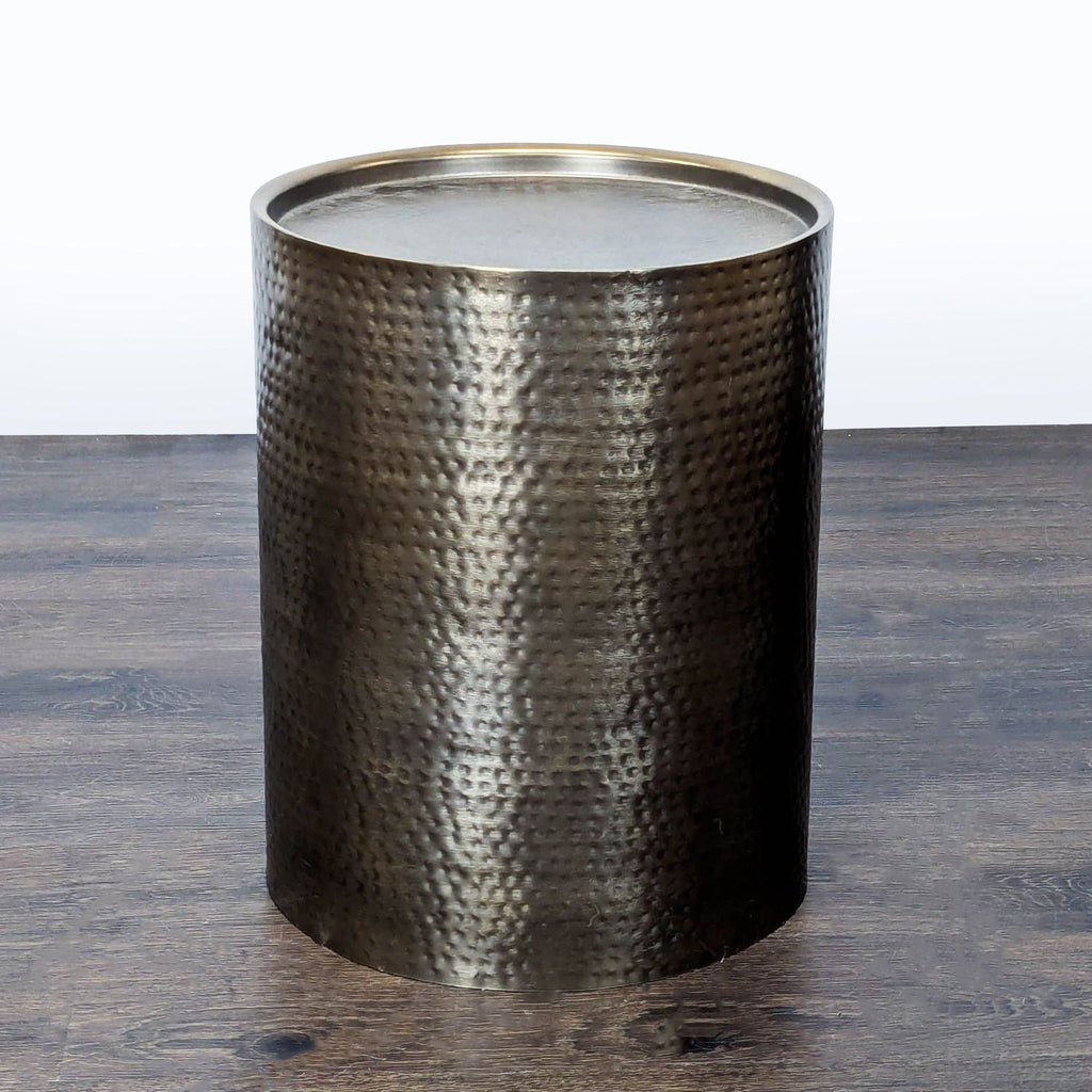 Drum-shaped metal side table with a hammered finish, circular top, and raised edges by Project 62.  
