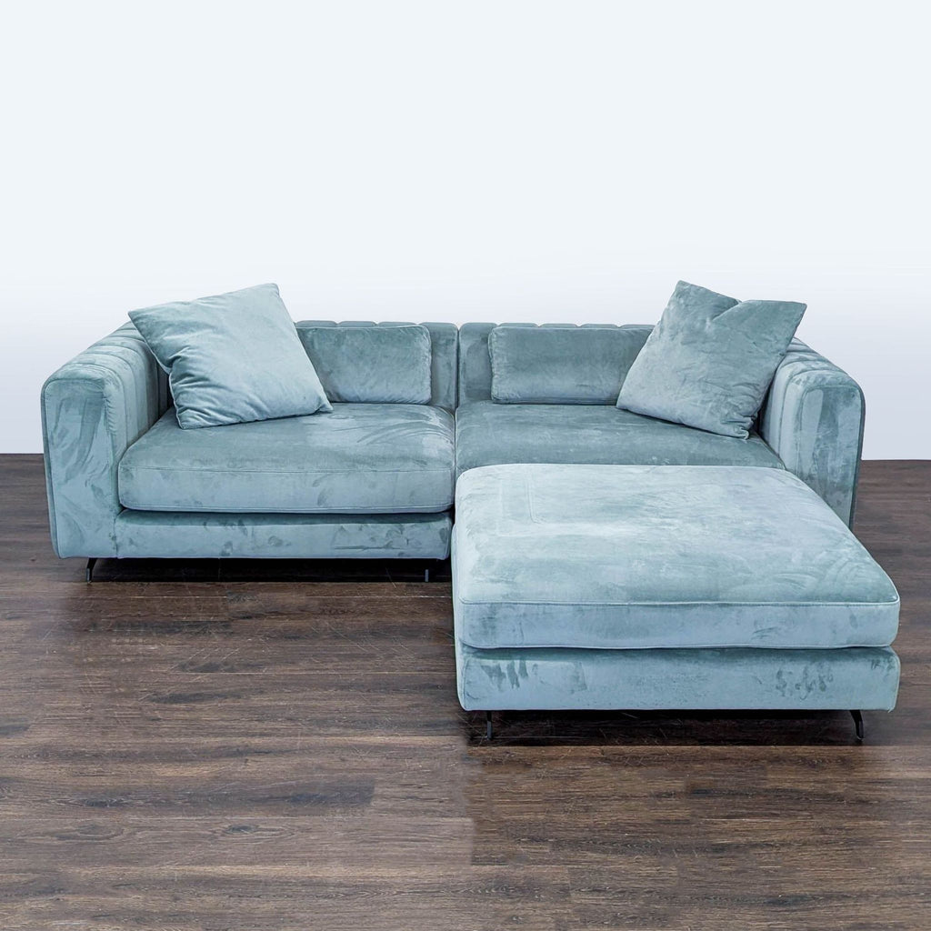Light blue velvet Rove Concepts sectional sofa with matching cushions and ottoman in a modern living room.