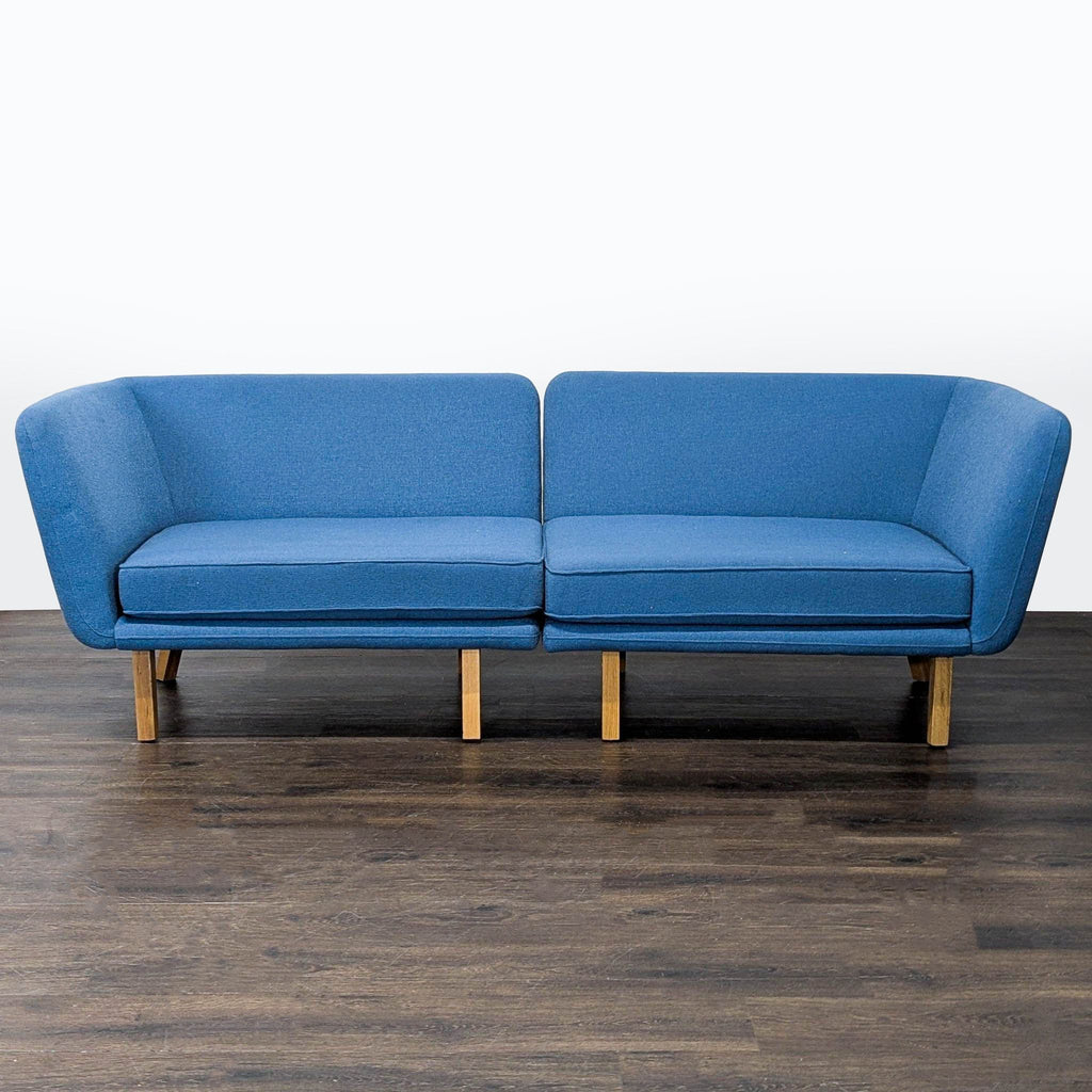 Modern blue Knoll sectional with clean lines and wooden legs, perfect for a stylish living room or office.  