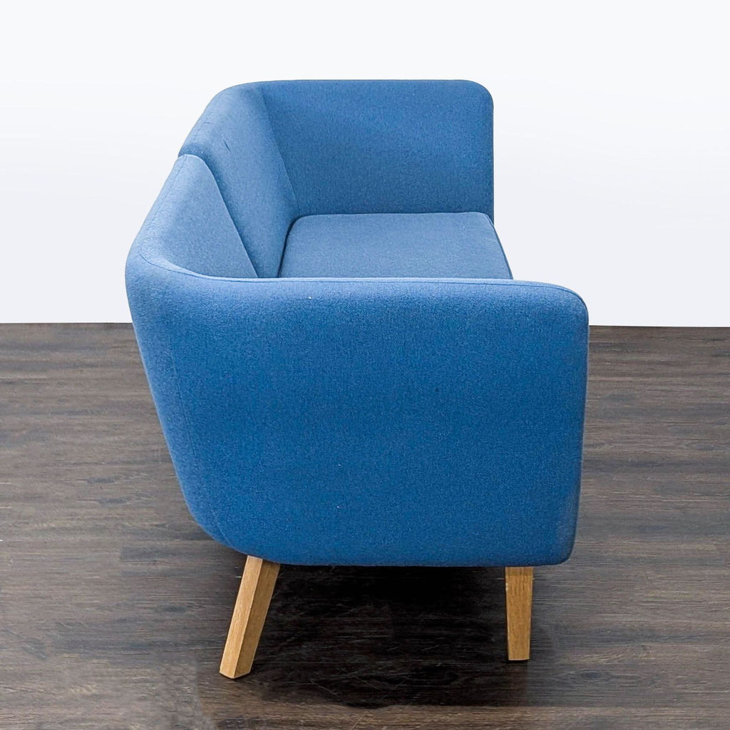 Side profile of a contemporary Knoll sectional in blue fabric, highlighting its sleek shape and solid wooden legs.