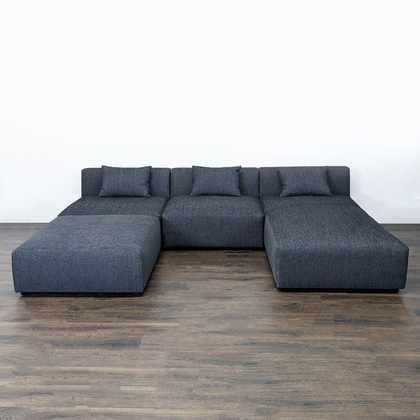 Modern dark gray Maiden Home sectional with chaise, ottoman, and pillows, ideal for stylish living room seating.