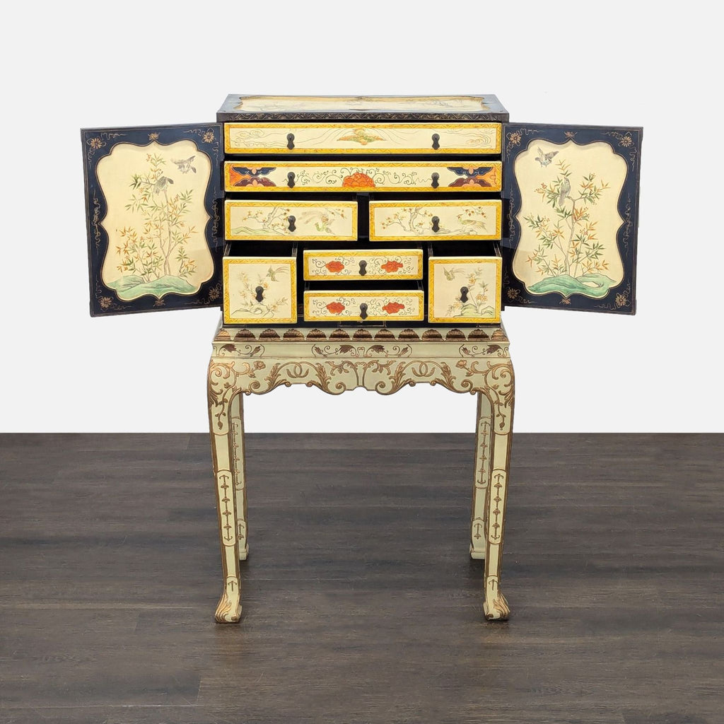 Decorative jewelry cabinet featuring detailed floral and bird designs, metal hardware, and a carved gold-accented base.  