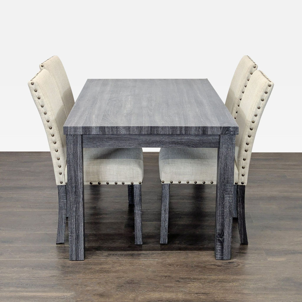 Gracie Oaks gray wood dining table with four beige, nailhead-trimmed chairs in a modern style.