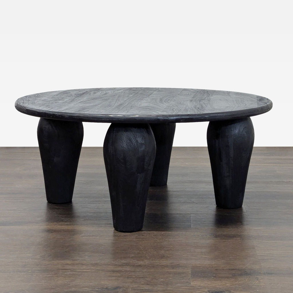 Modern coffee table by Four Hands features substantial legs and a rounded, light black reclaimed wood surface.