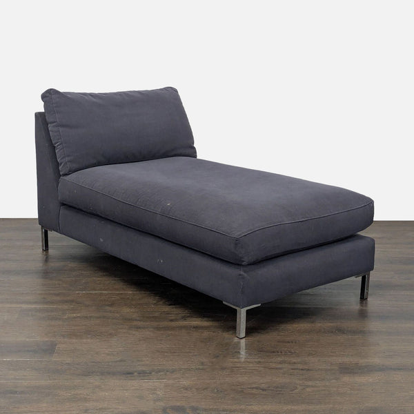 Modern CB2 chaise lounge with dark gray upholstery, plush cushion, and metal legs for a sleek, contemporary style.