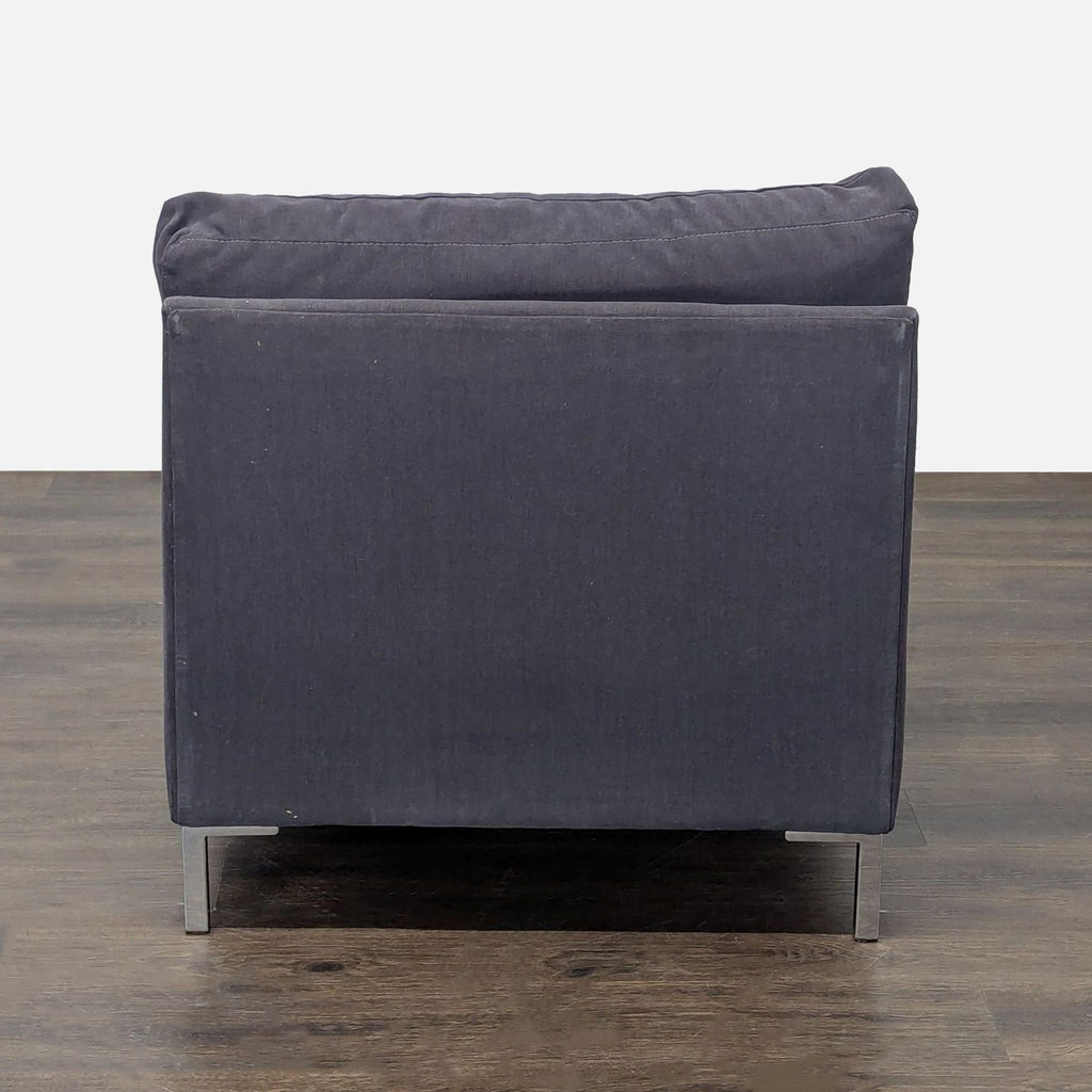 Contemporary dark gray CB2 chaise with plush seating, metal legs, and minimalist design for relaxation or reading.