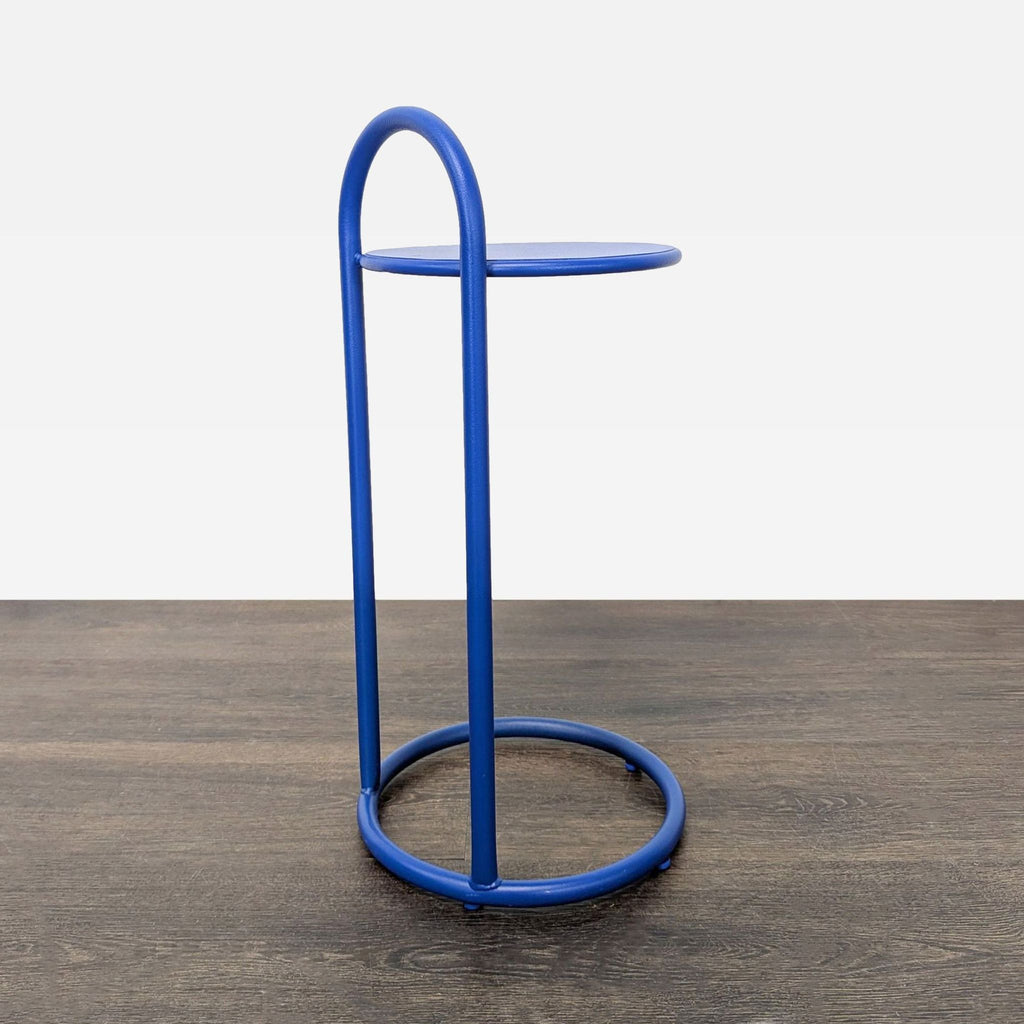 3. Contemporary blue side and console table with a rounded top and open circular metal frame on dark flooring.
