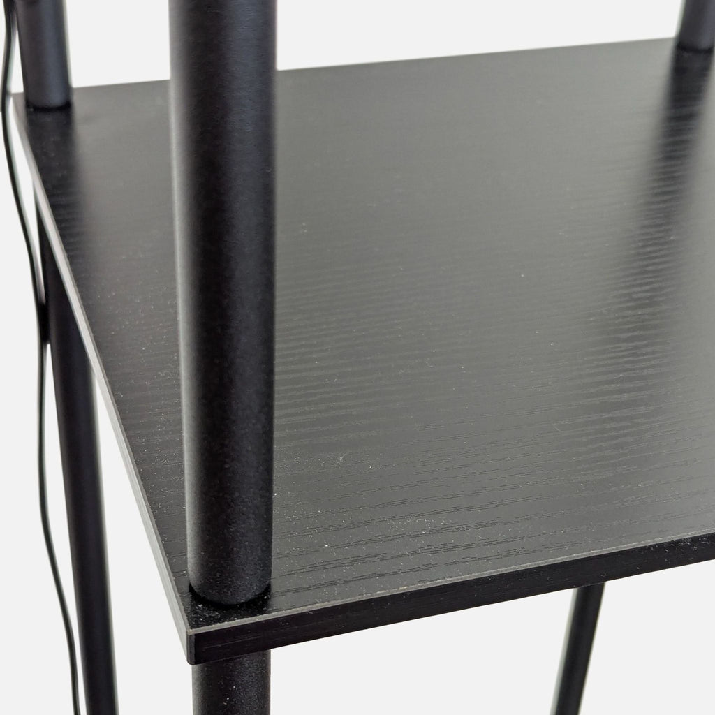 Close-up of a sturdy black shelf section on a floor lamp, showing smooth finish and supporting vertical rods.